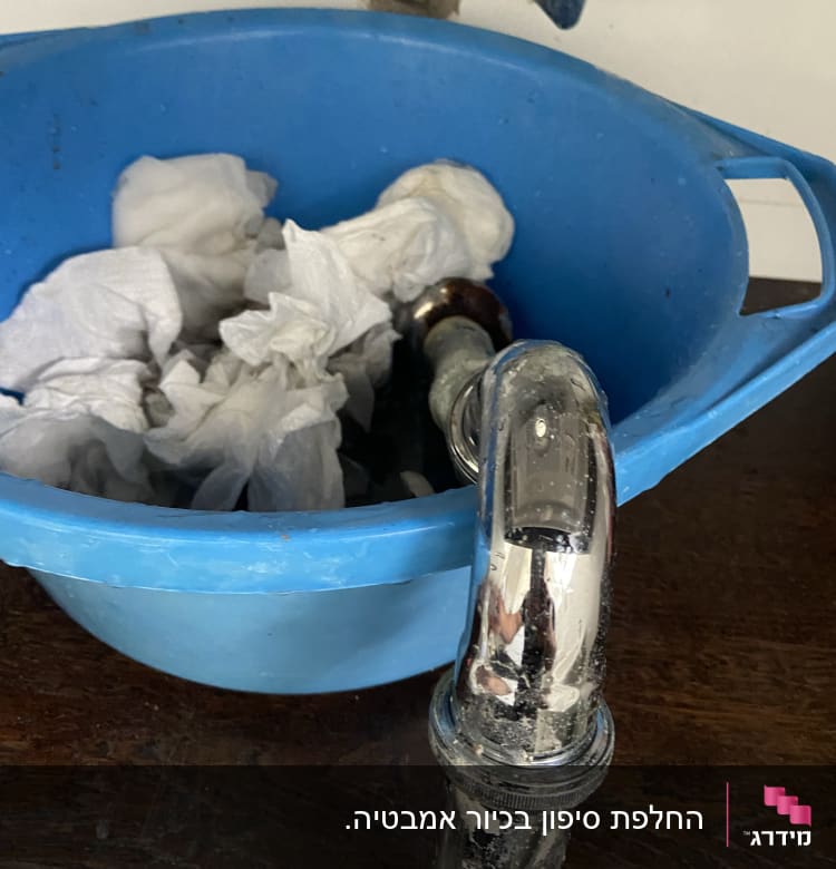 כיור עם ברז מנותק ודלי כחול עם ניירות